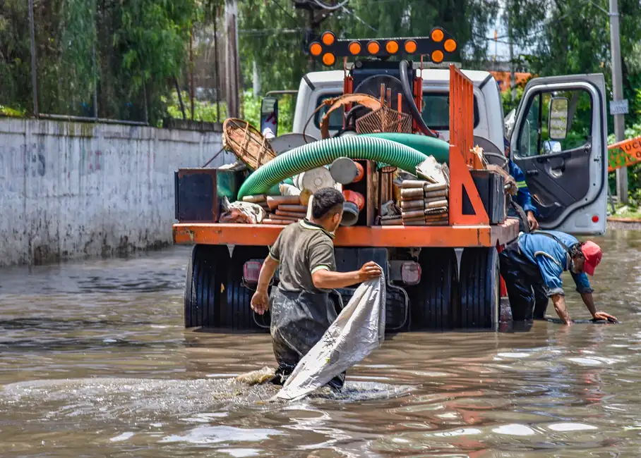 Crew with a pump truck and hoses working in a flooded street during emergency water removal